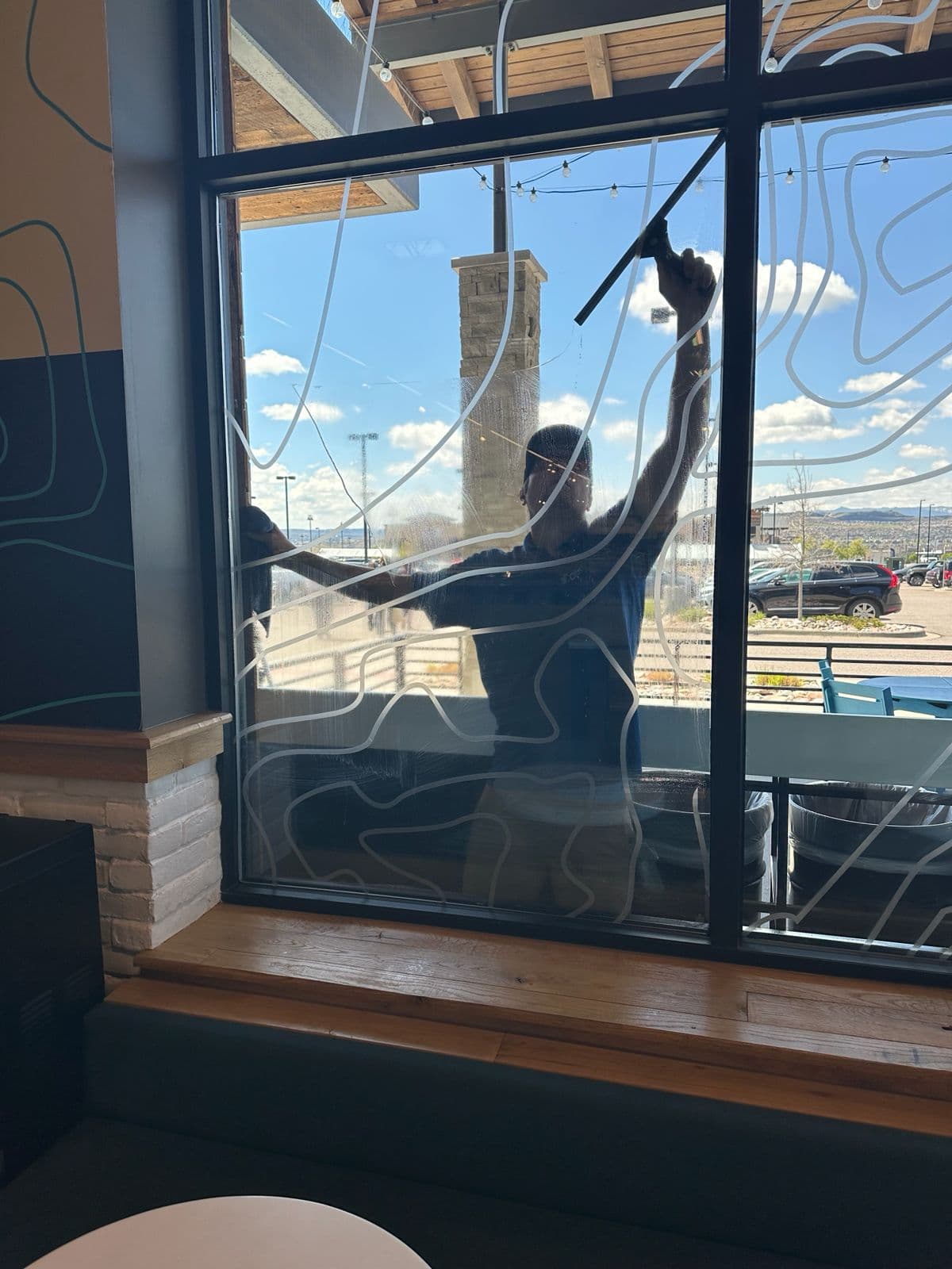 Kathy Clean technician squeegeeing the exterior window of a Starbucks cafe in Denver